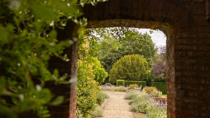 View of a floral garden through a bricked arch